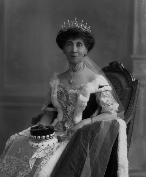 an old black and white photo of a woman in a tiara sitting on a chair