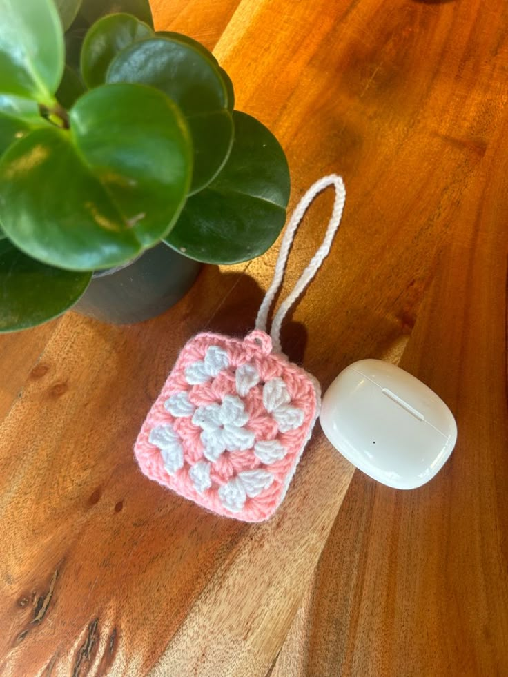 a small crocheted square is sitting on a table next to a computer mouse