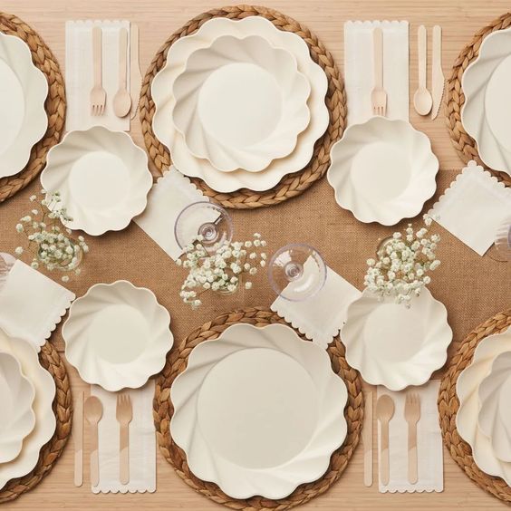 the table is set with white plates and silverware, napkins and baby's breath flowers