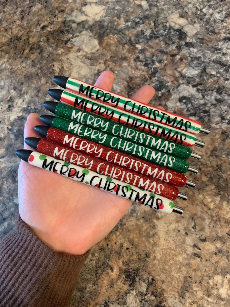 a person holding four christmas pencils in their hand