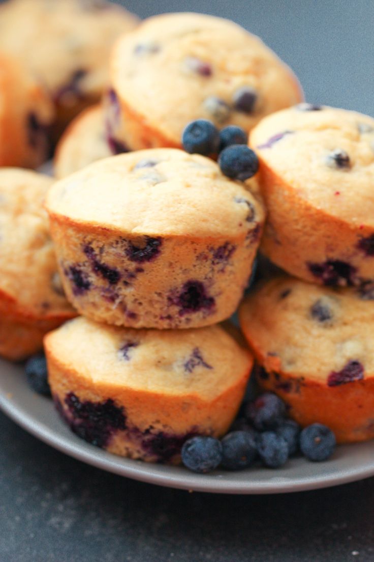 blueberry muffins stacked on top of each other in a plate with fresh blueberries