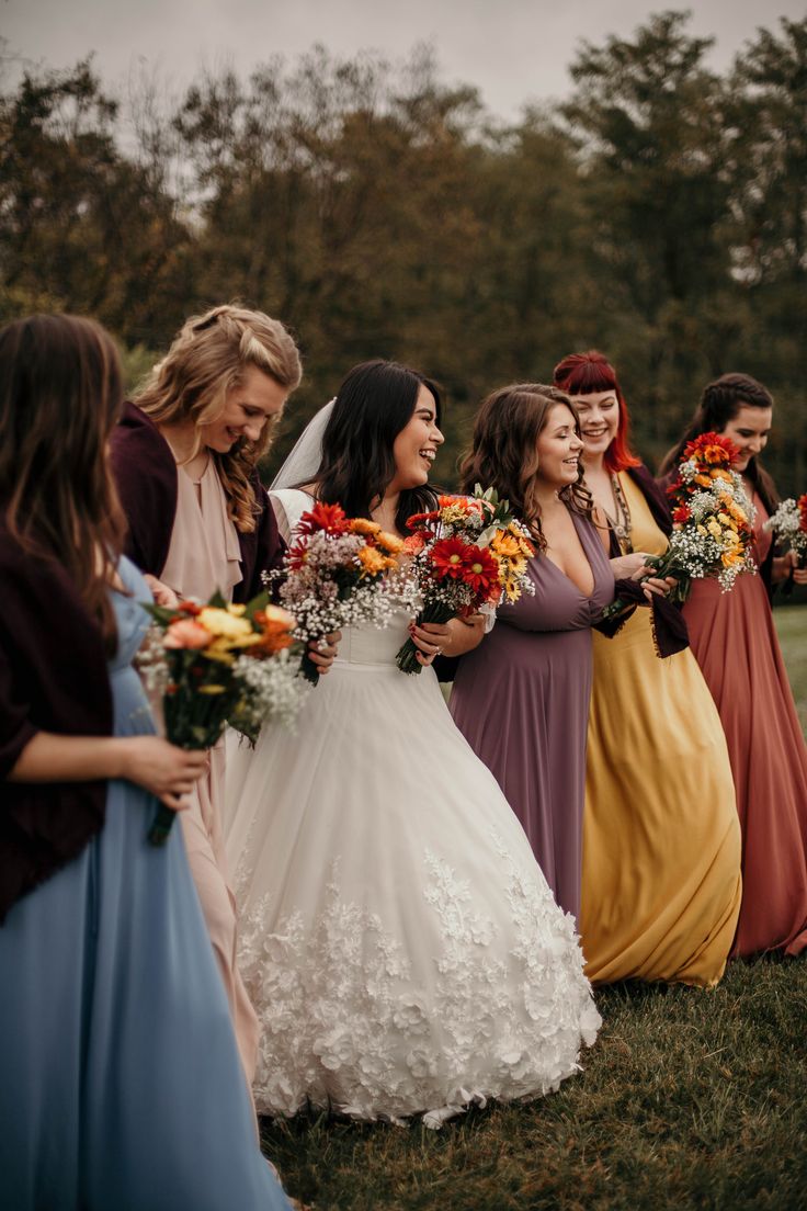 a group of women standing next to each other holding bouquets in their hands and laughing