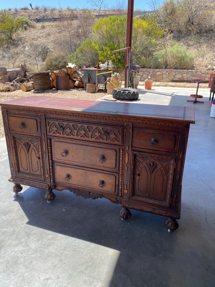 an old wooden buffet table sitting in the middle of a patio