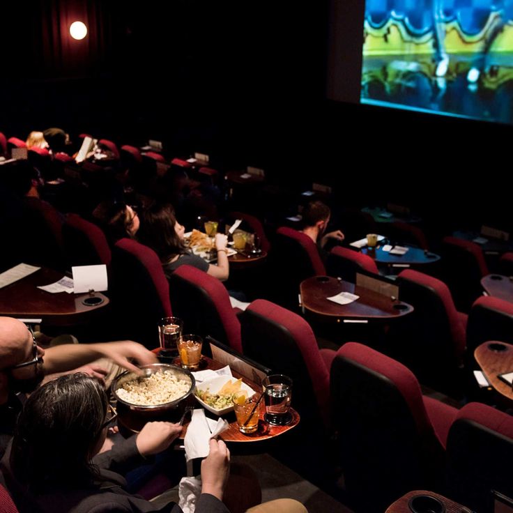 people are sitting in the movie theater and eating their meals on trays while watching television