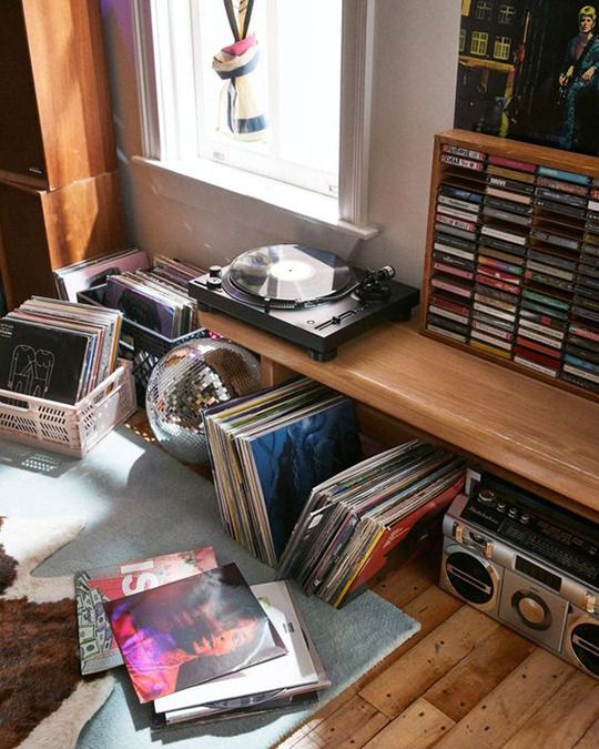 there are many records on the shelf next to the radio and record player in the room