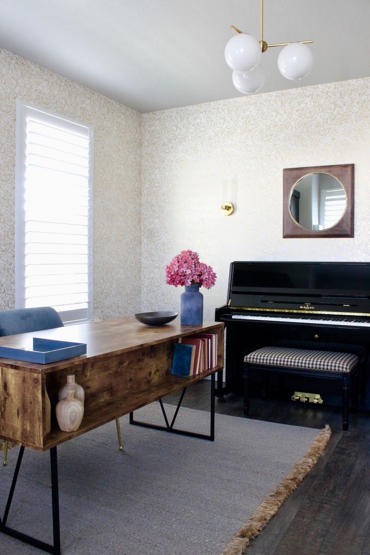 a living room with a piano, mirror and vase on the table in front of it