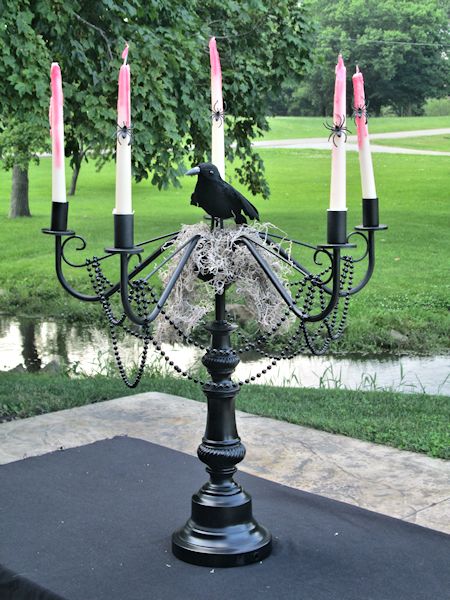 a candelabra with candles and a crow on it in the middle of a park