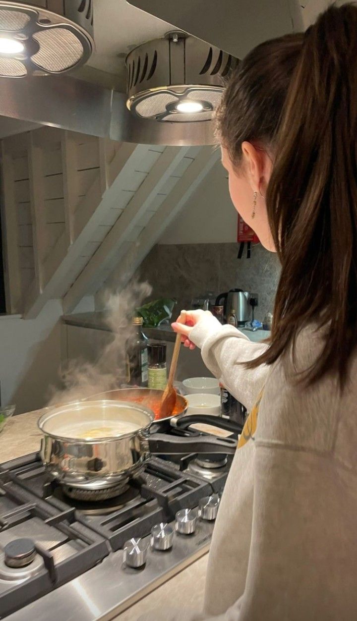 a woman is cooking on the stove with steam coming out of her pan and holding a wooden spoon