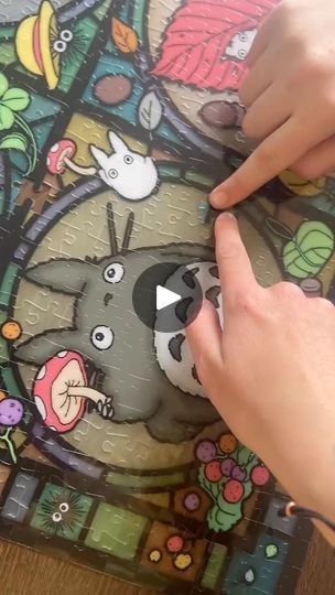 a person is pointing at a puzzle with an animal on it and another hand holding the piece