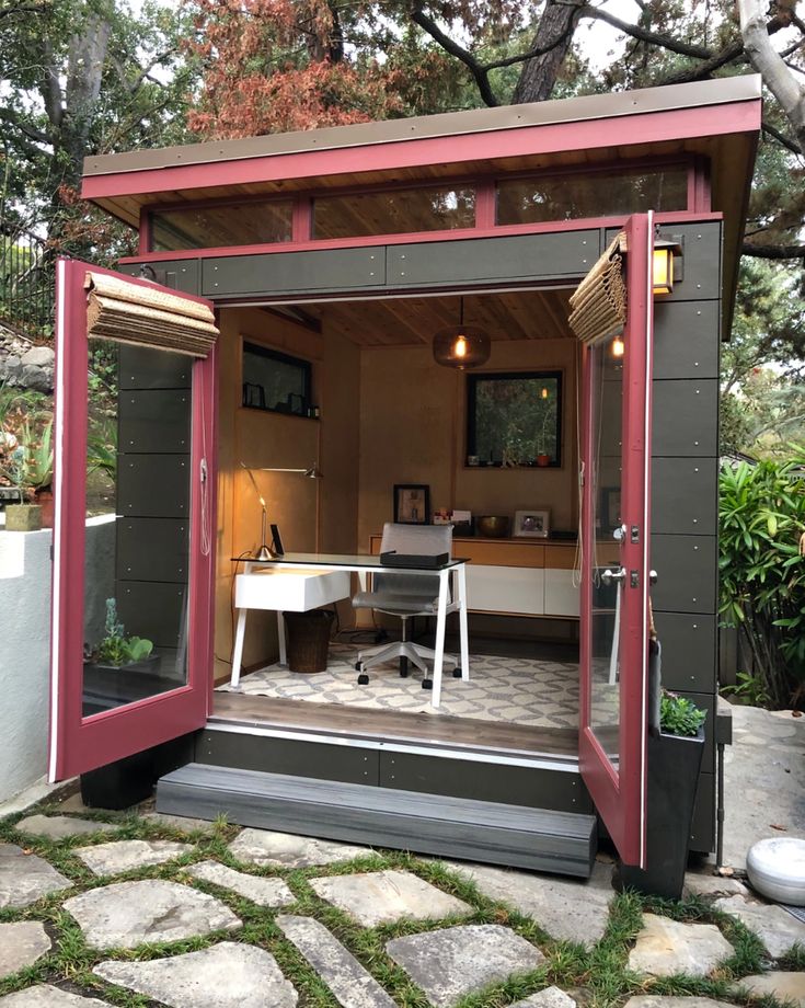 a small garden shed with the door open to reveal a desk and chair in it