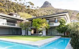 an outdoor swimming pool in front of a large house with mountains in the back ground