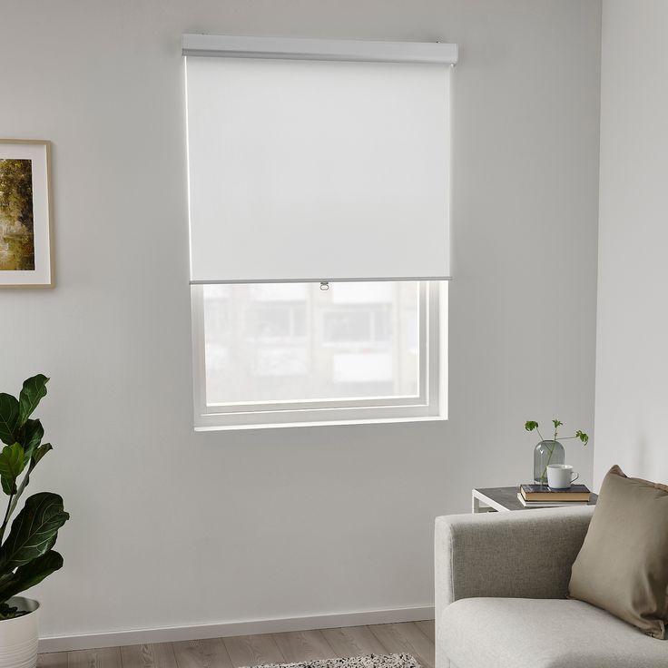 a living room with a couch, chair and white window coverings on the windowsill