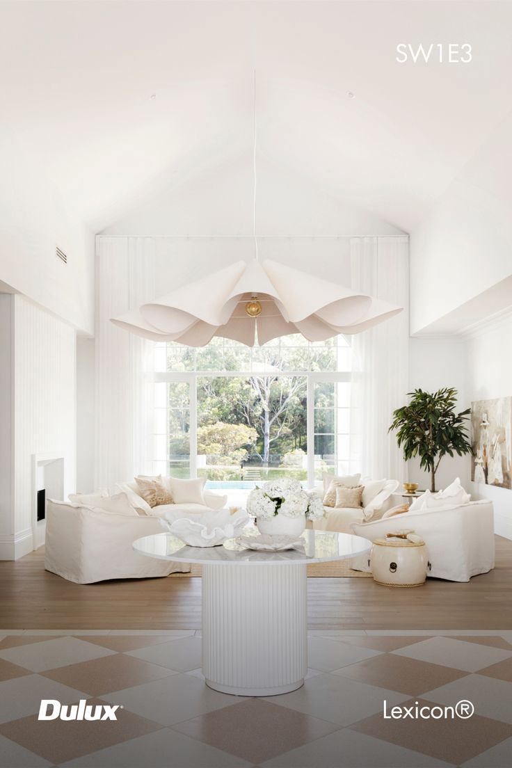 a living room filled with white furniture next to a large open floor plan and windows