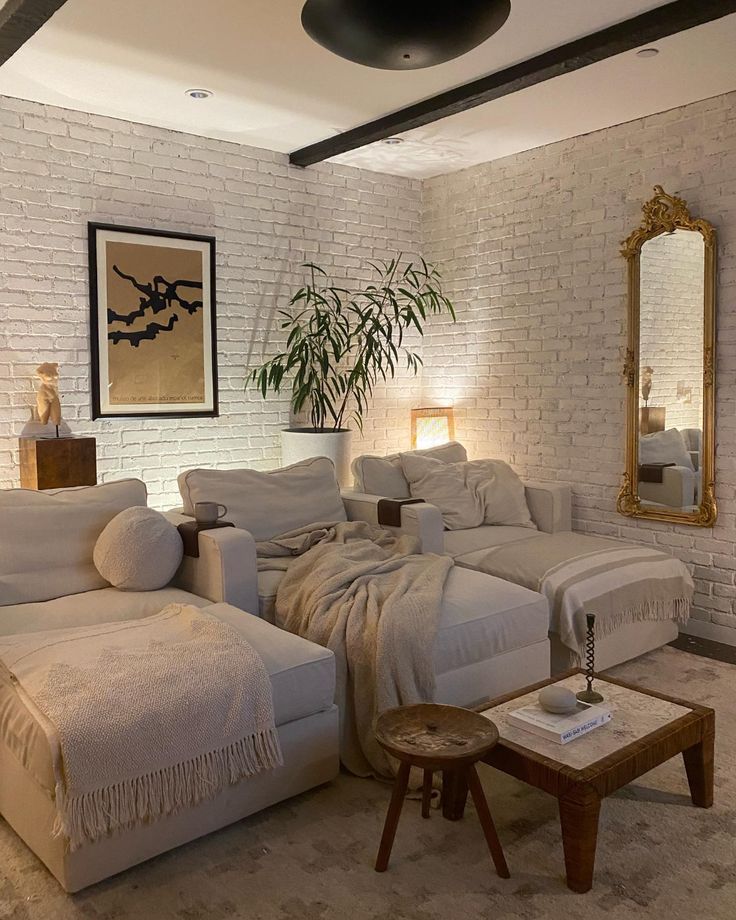 a living room filled with white furniture and a large mirror on top of the wall