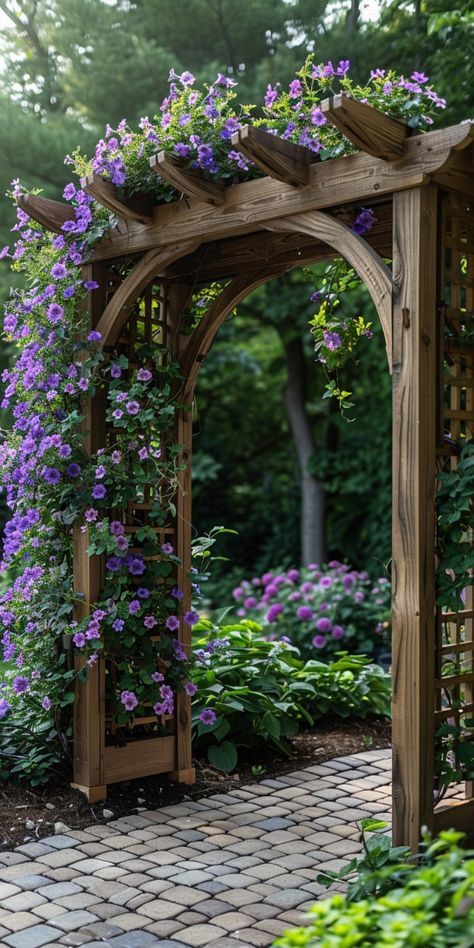 a wooden arbor with purple flowers growing on it's sides and brick walkway in the foreground