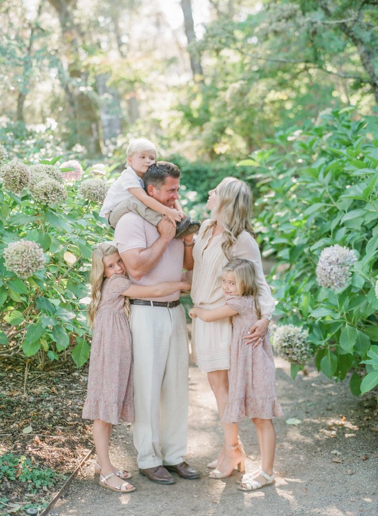 a family standing together in the middle of a forest with trees and bushes behind them