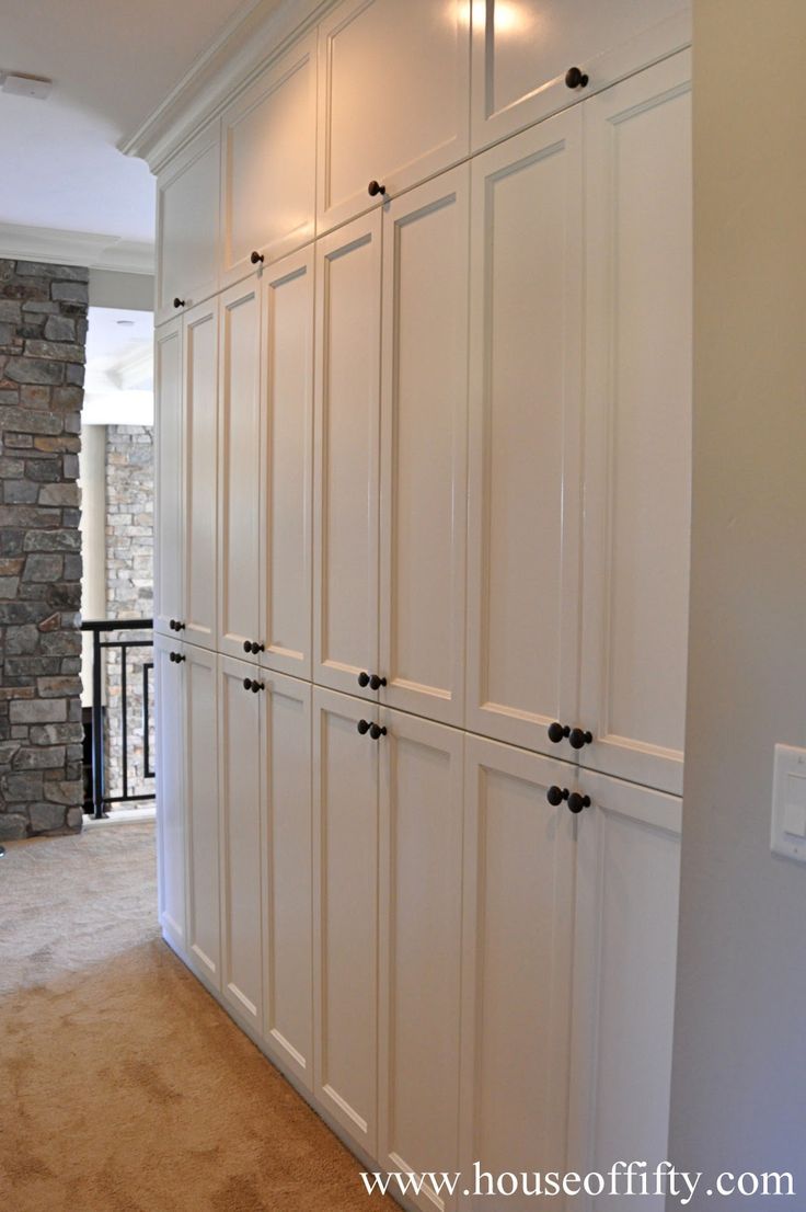 an empty room with white cupboards and stone wall in the backround area