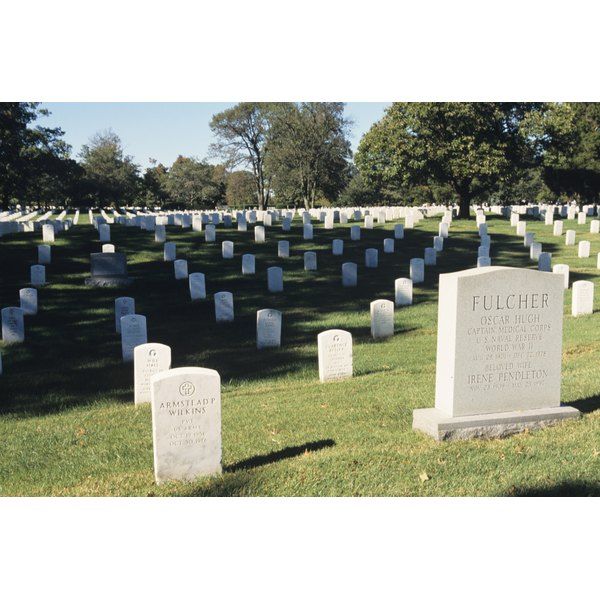 several headstones in a cemetery with trees in the background and grass on the ground