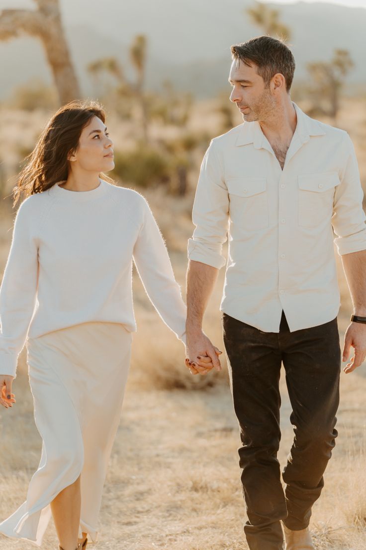 a man and woman walking in the desert holding hands