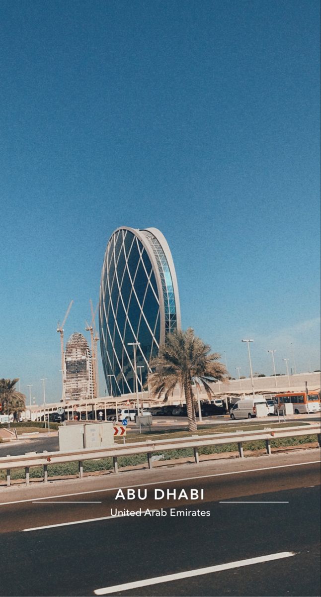 an empty street in front of a tall building with palm trees on the other side