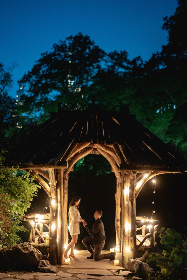 two people standing under a lit up gazebo