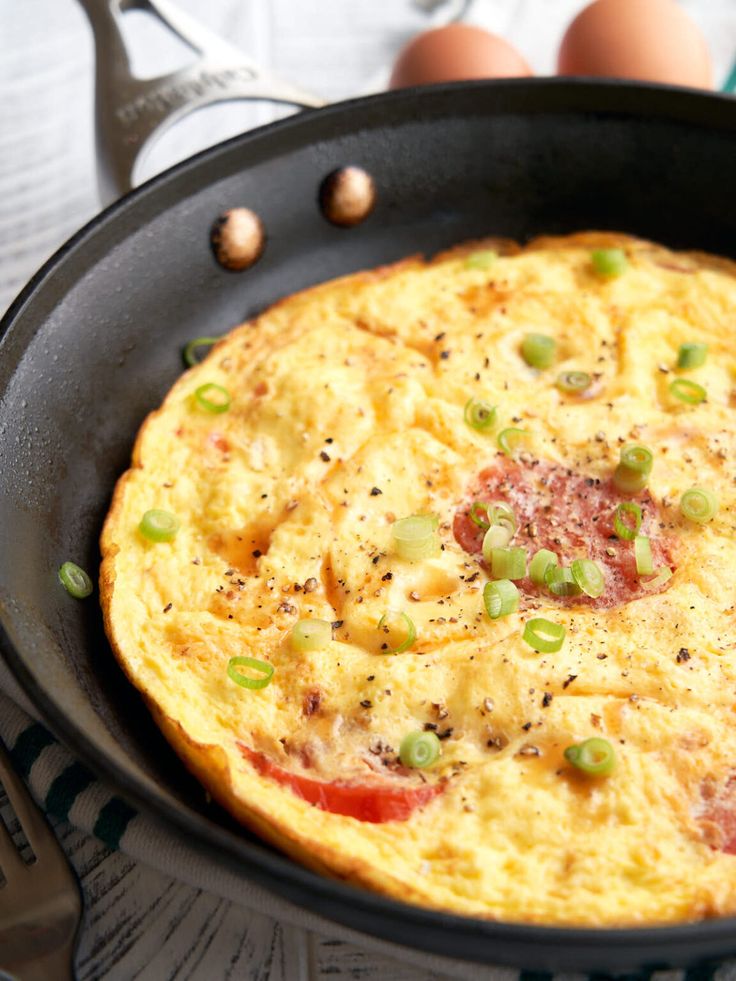 an omelet in a skillet with peas and other toppings on the side