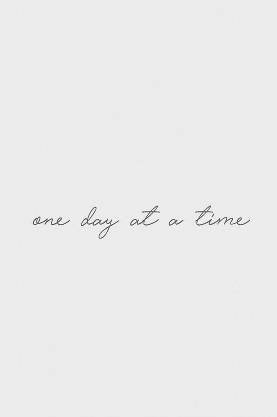 one day at a time written in cursive writing on a white paper background