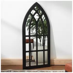 an arched mirror on the wall with a plant in it