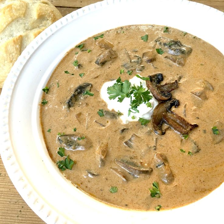 a bowl of mushroom soup with sour cream and parsley on the top, ready to be eaten