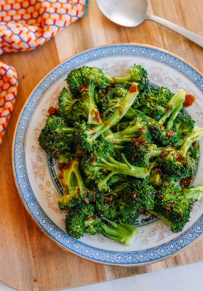 a plate with broccoli on it next to spoons and napkins in the background