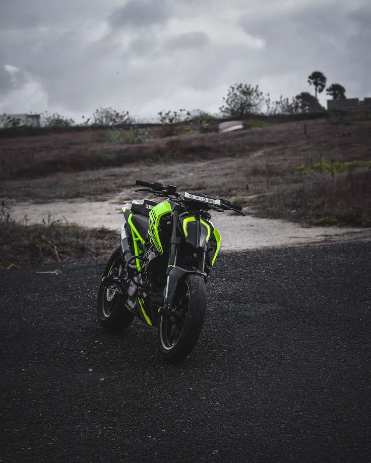 a yellow and black motorcycle parked on the side of a road in front of a field