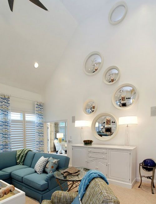 a living room filled with furniture and lots of mirrors on the wall above it's windows