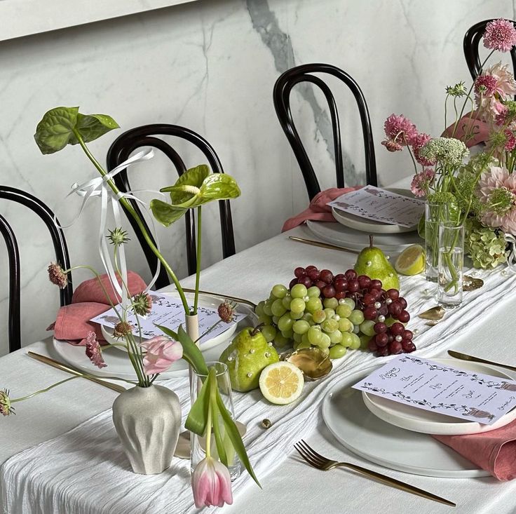 the table is set with flowers and fruit