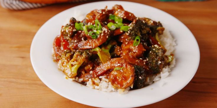 a white plate topped with rice covered in meat and veggies on top of it