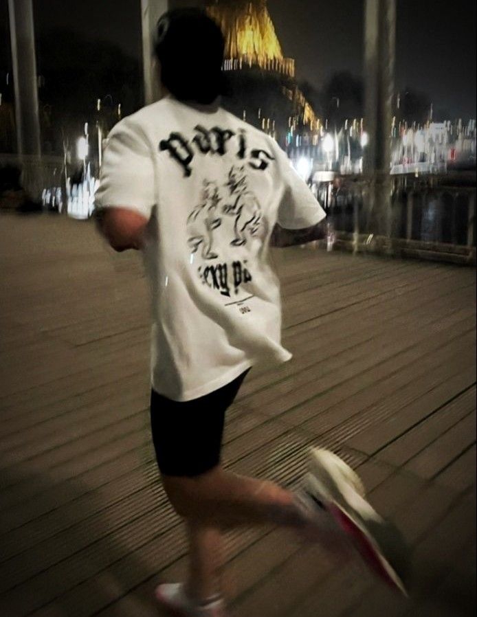 a man is running on the boardwalk at night with his shoes in front of him