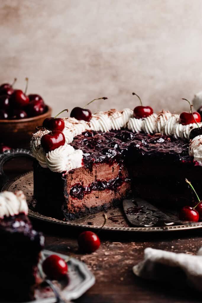 a chocolate cake topped with cherries and whipped cream