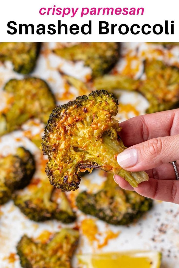 a hand holding up a piece of broccoli to show the crispy parmesan smashed broccoli