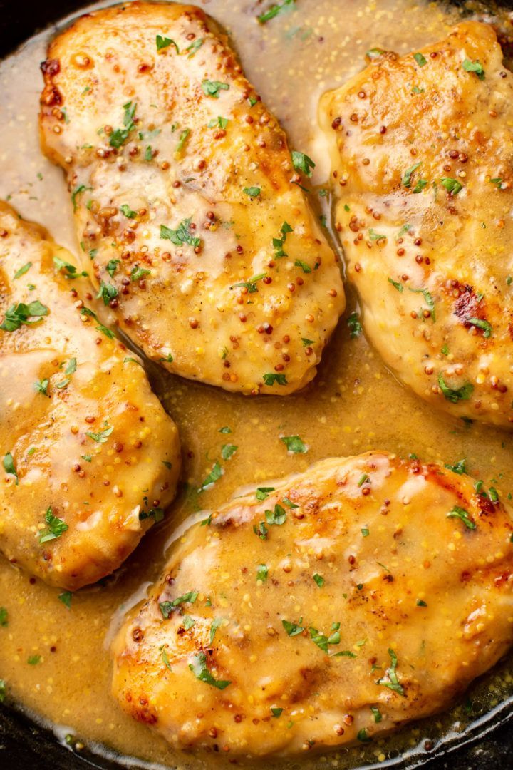 some chicken is cooking in a skillet with gravy on the top and parsley on the side