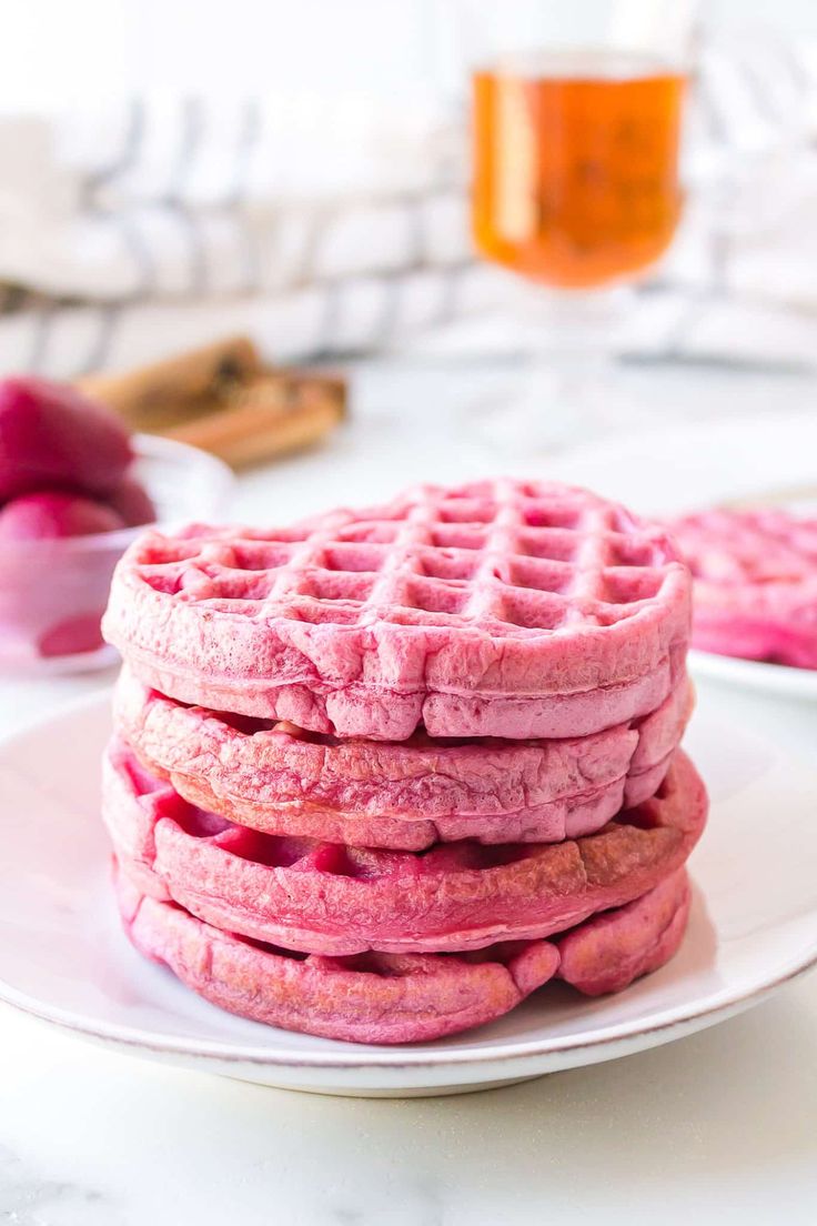 a stack of pink waffles sitting on top of a white plate