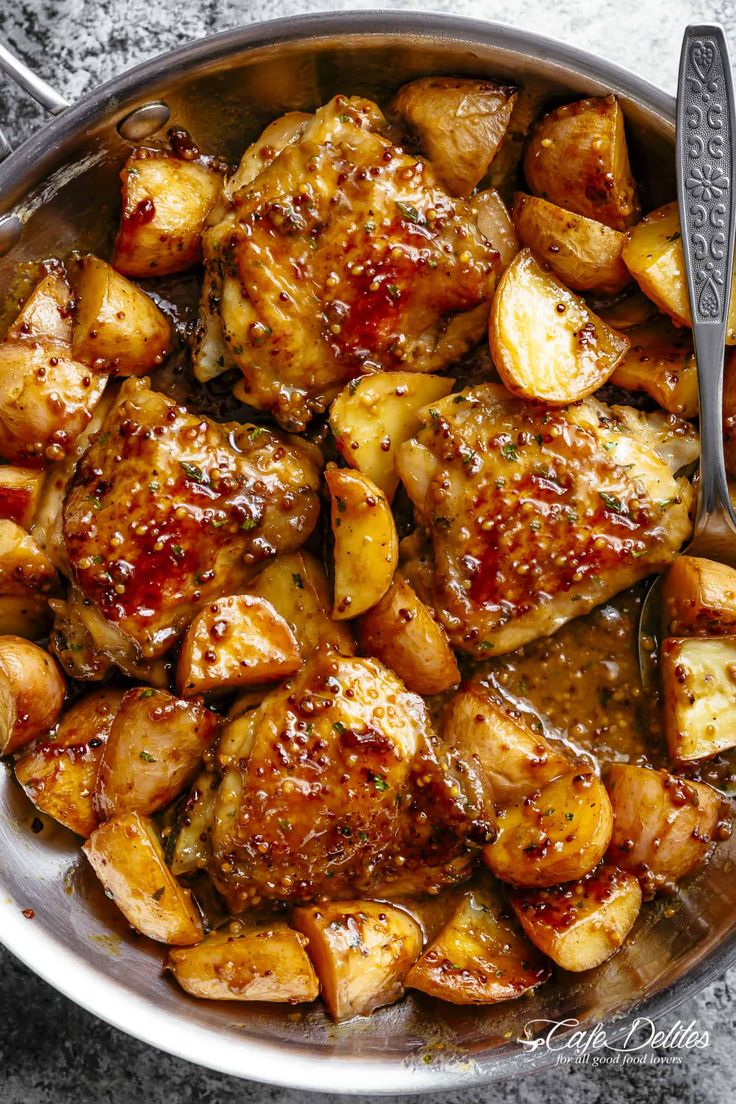 a pan filled with chicken and potatoes covered in bbq sauce next to a fork