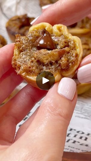 a person holding a pastry with chocolate on it's top and an olive in the middle