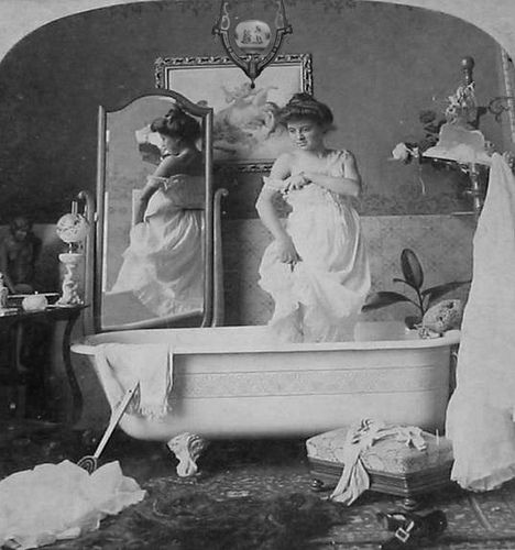 an old photo of two women standing in front of a bathtub