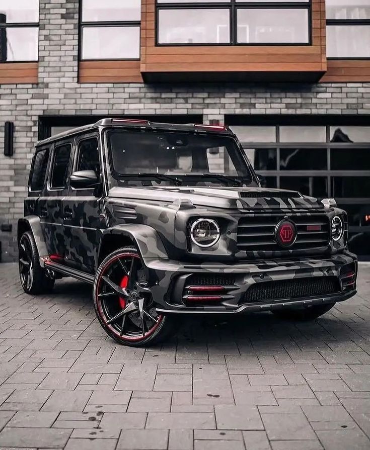 the mercedes g - class is camouflaged with red rims and chrome wheels,