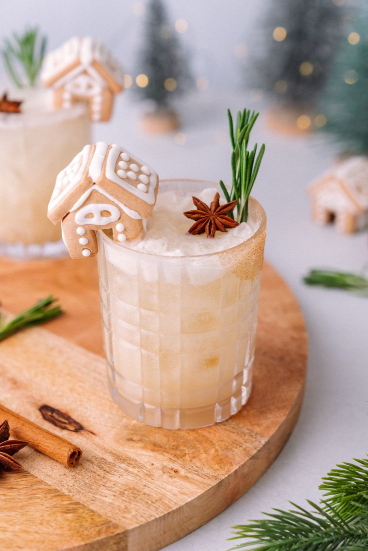 two glasses filled with drinks on top of a wooden tray next to christmas decorations and greenery