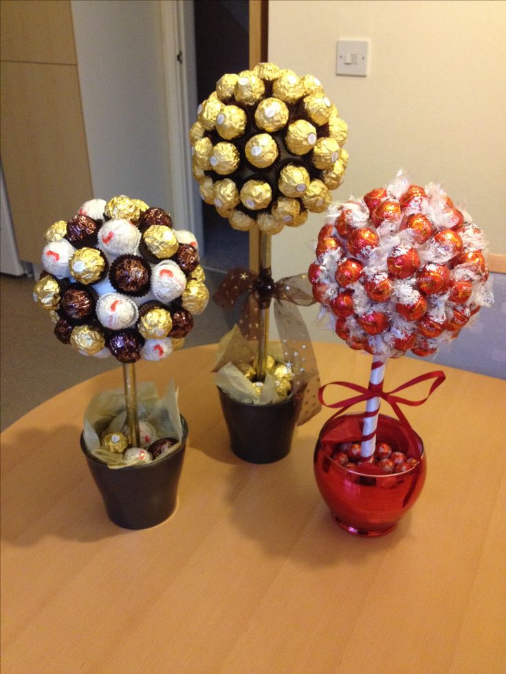 three vases filled with candy and candies on top of a round wooden table