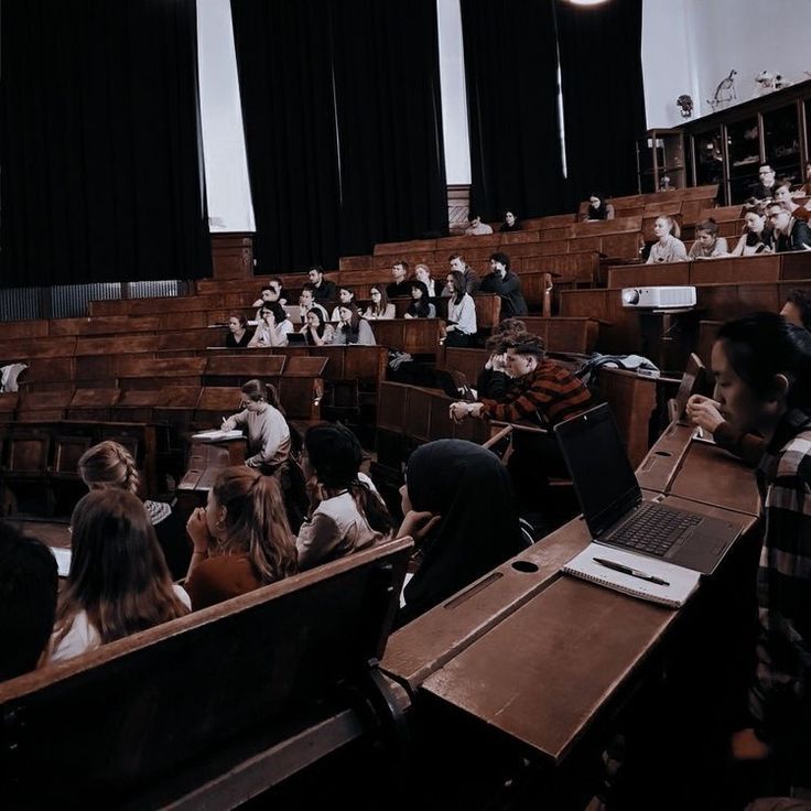 an auditorium full of students sitting at desks with laptop computers in front of them