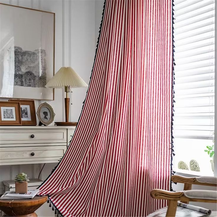 a red and white striped shower curtain in a living room with a chair, table and lamp