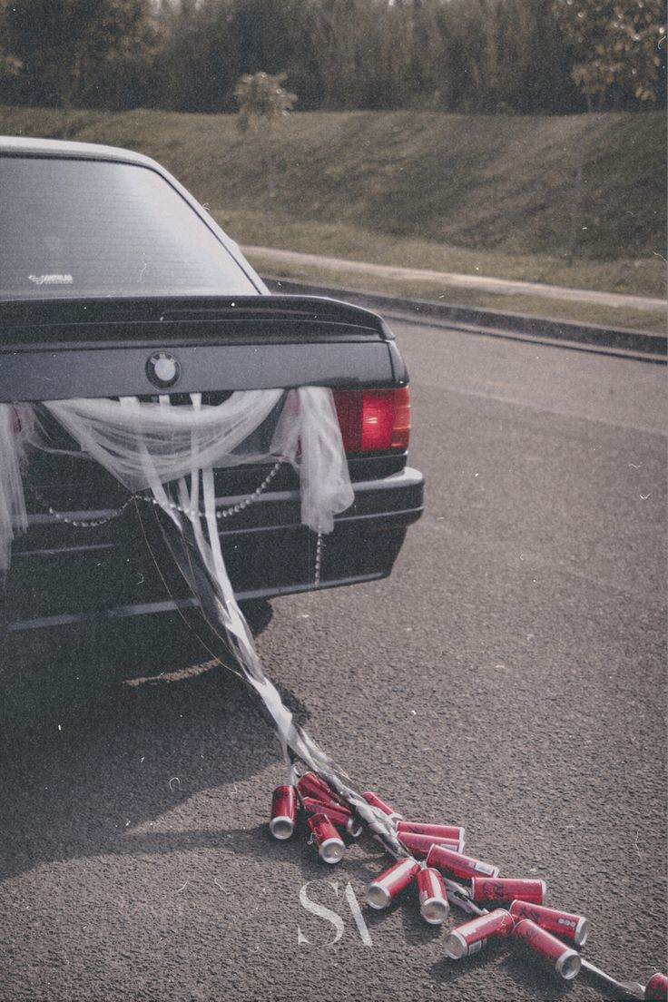 a car parked on the side of the road with wedding decorations tied to it's bumper