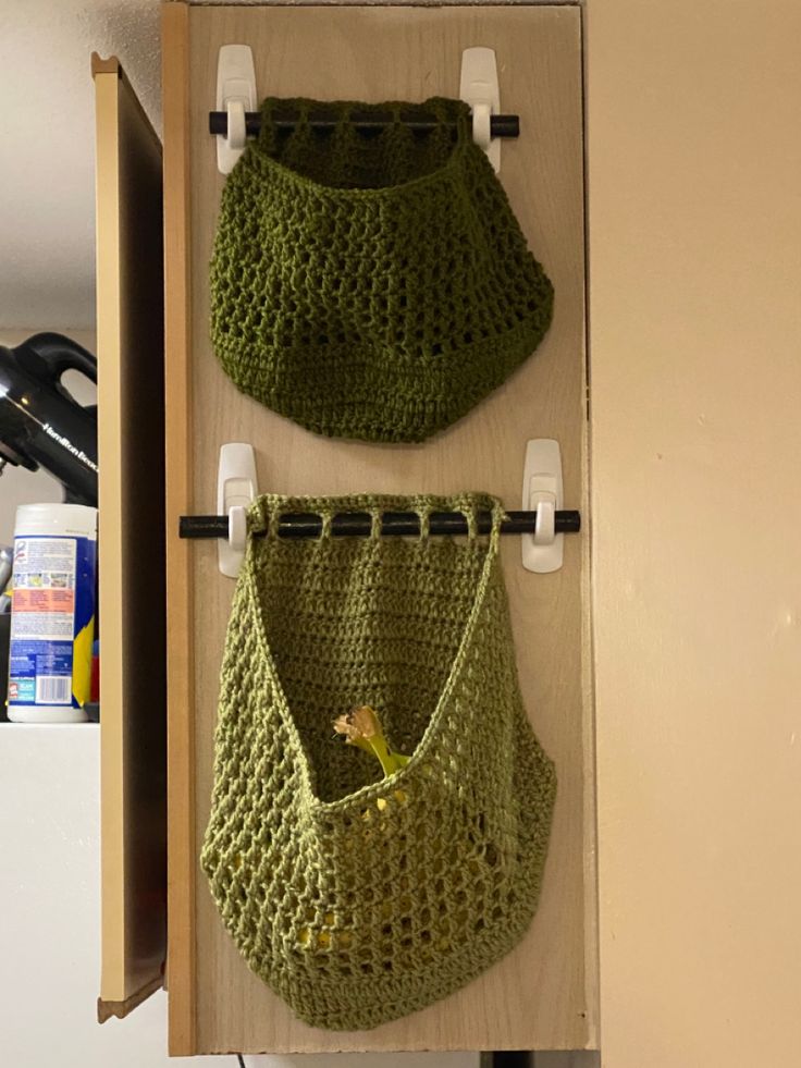 two crocheted purses hanging from hooks on a wall