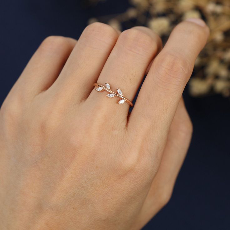 a woman's hand wearing a gold ring with leaves on it